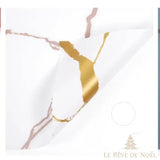 Papier cadeau effet marbre blanc veiné de mauve, coin replié laissant voir une veine dorée