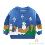 Pull de Noël enfant bleu à bonhomme de neige, sapins et flocons brodés, présenté à plat