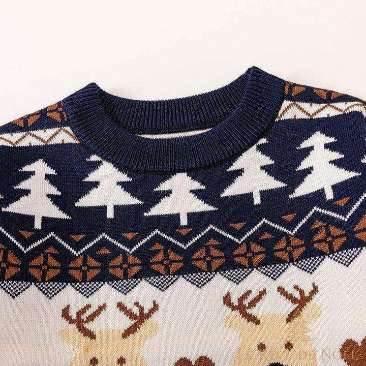 Gros plan sur le col côtelé bleu marine du pull, motifs sapins et rennes en tricot jacquard