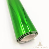 Papier cadeau métallisé vert brillant, enroulé en rouleau montrant l'envers blanc du papier