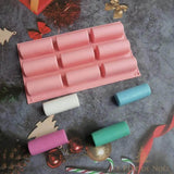 Moule à bûche en silicone rose à neuf empreintes, avec quatre barrettes de cire colorées devant