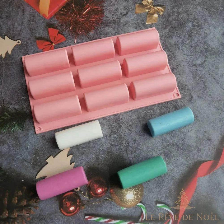 Moule à bûche en silicone rose à neuf empreintes, avec quatre barrettes de cire colorées devant