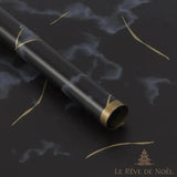 Rouleau de papier cadeau effet marbre noir et gris, entouré de rubans dorés bouclés