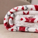 Gros plan sur le plaid polaire roulé, motifs flocons rouges et envers moelleux blanc