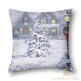 Housse de coussin en tons gris, sapin enneigé devant une maison illuminée la nuit