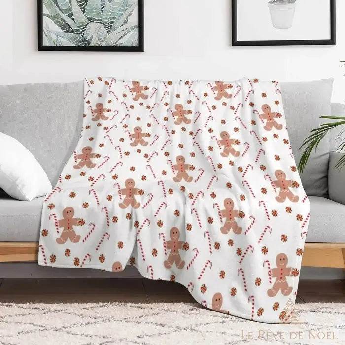 Plaid beige à motifs bonhommes en pain d'épice et sucres d'orge, drapé sur un canapé gris