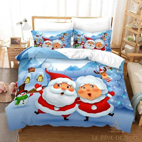 Lit habillé d'une housse de couette bleue à motif Père Noël et Mère Noël dessinés, deux taies assorties