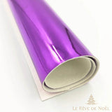 Papier cadeau métallisé violet brillant, enroulé en rouleau montrant l'envers blanc du papier