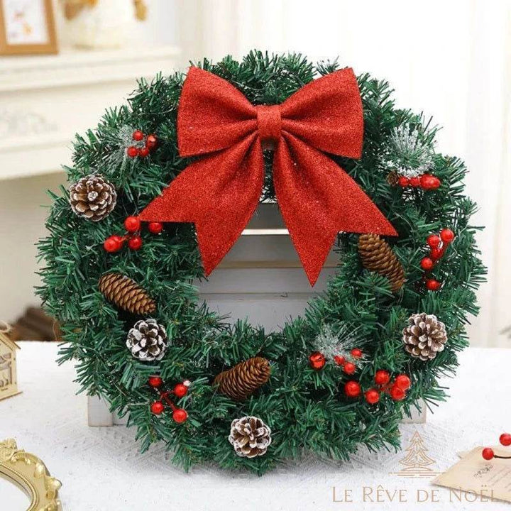 Couronne de Noël sans éclairage, nœud rouge pailleté, debout devant une cheminée