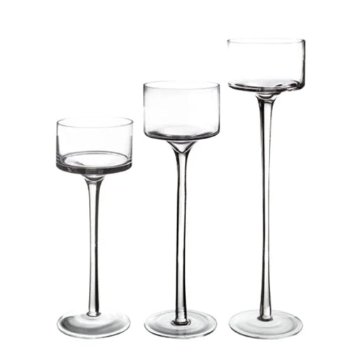 Trois bougeoirs en verre transparent de hauteurs différentes, alignés sur fond blanc