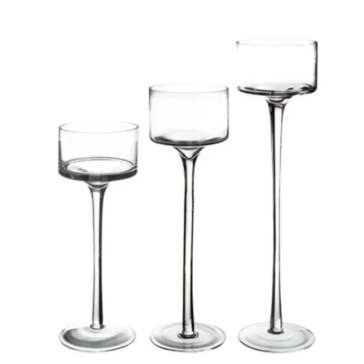 Trois bougeoirs en verre transparent de hauteurs différentes, alignés sur fond blanc