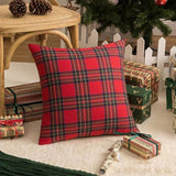Housse de coussin tartan rouge à carreaux verts et bleus, posée au sol près de cadeaux