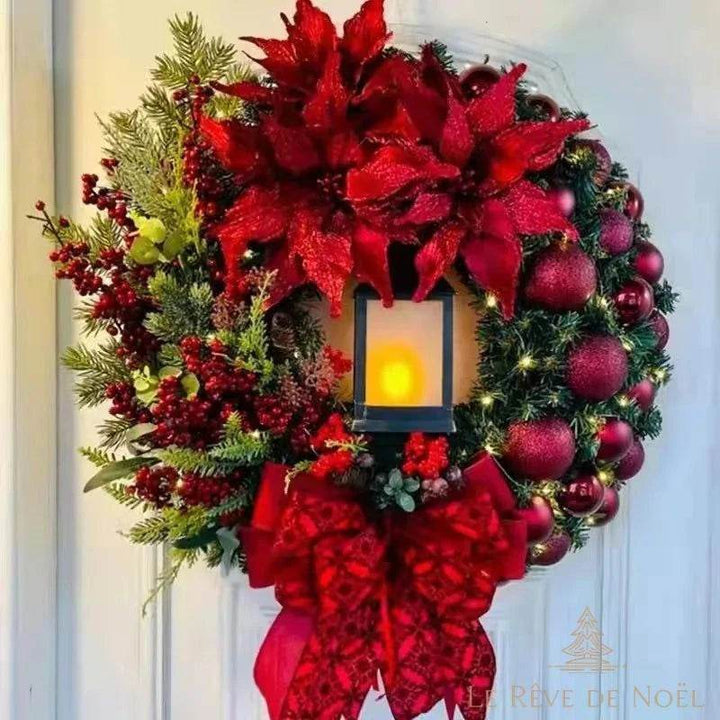 Couronne de Noël rouge avec lanterne lumineuse, boules et fleurs rouges, sur une porte