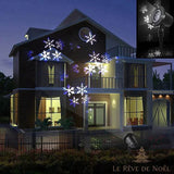 Projecteur LED sur piquet projetant des flocons de neige sur la façade d'une maison la nuit