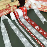 Rubans organza rouges et blancs à flocons devant des rouleaux de papier cadeau de Noël
