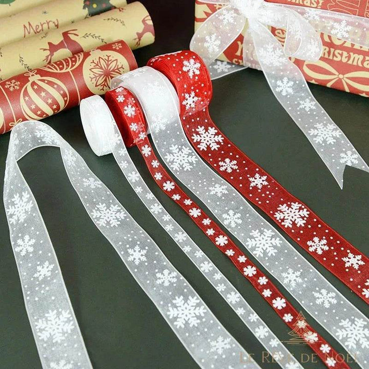 Rubans organza rouges et blancs à flocons devant des rouleaux de papier cadeau de Noël
