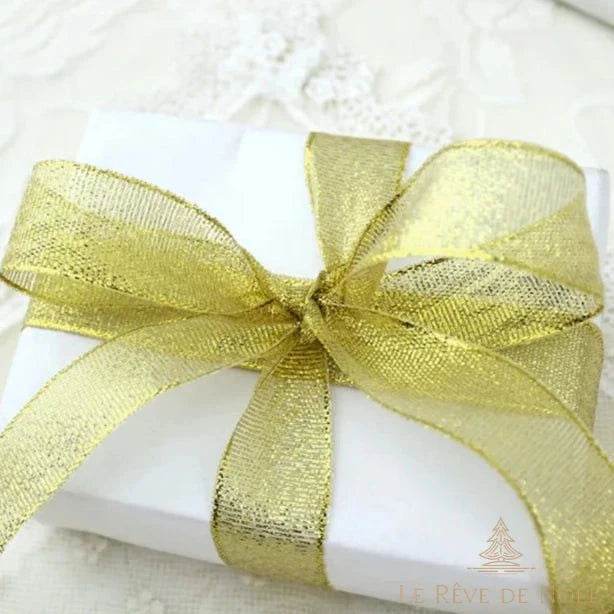 Boîte cadeau blanche nouée d'un large ruban doré scintillant en organza