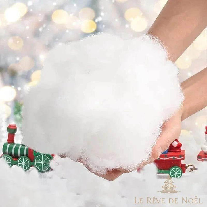 Neige artificielle blanche façon ouate tenue à deux mains, décor de Noël flouté en arrière-plan