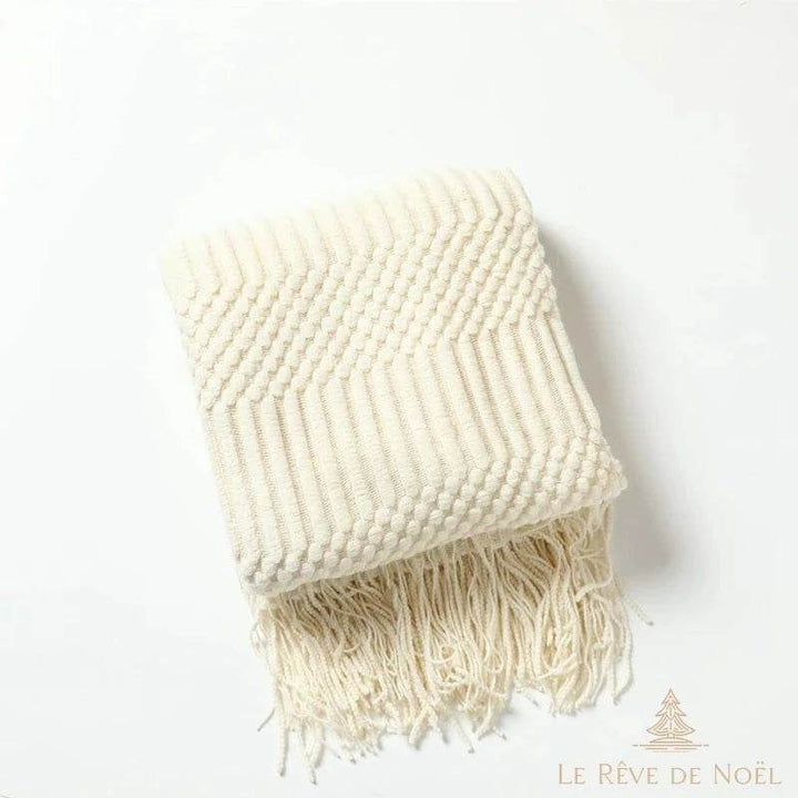 Plaid de Noël ivoire plié, texture en chevrons et picots tricotés, longues franges torsadées