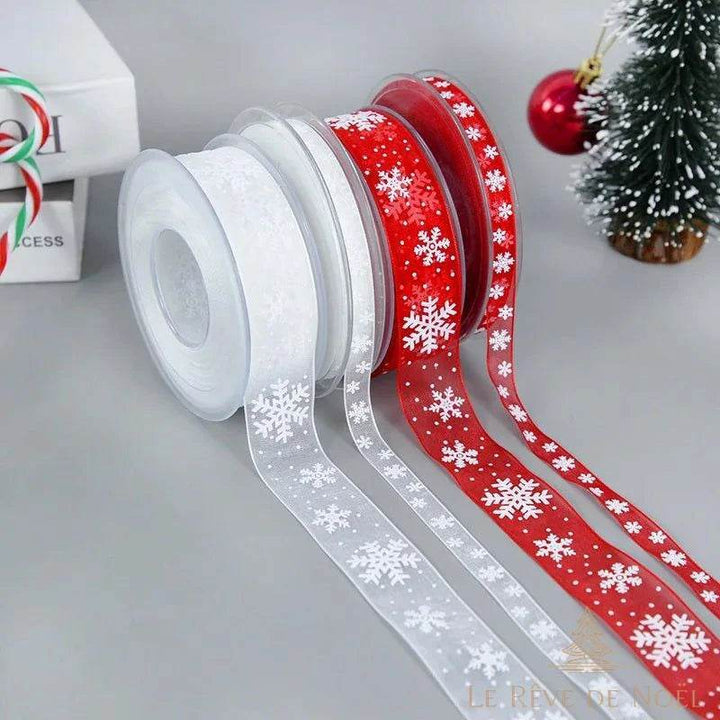 Quatre bobines de ruban organza à flocons, blanc et rouge, devant un petit sapin enneigé