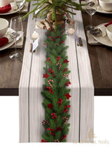 Chemin de table à motif bois clair, guirlande de sapin et baies rouges peintes au centre