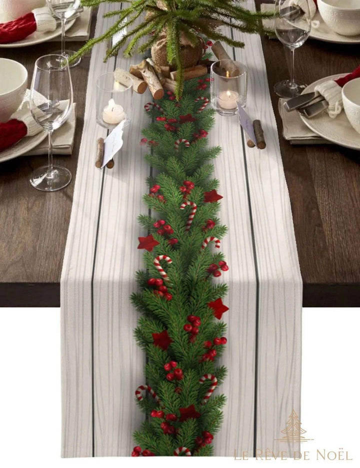 Chemin de table à motif bois clair, guirlande de sapin et baies rouges peintes au centre