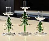 Trois bougeoirs sapin en verre de tailles différentes, sans bougie, sur un plan de travail