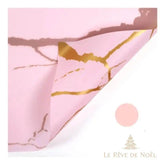 Papier cadeau effet marbre rose pâle, coin replié laissant voir une large veine dorée