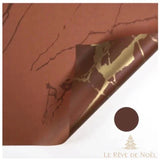 Papier cadeau marron terracotta effet marbre, coin replié sur un brun plus foncé veiné d'or