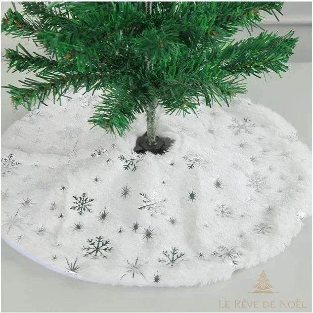 Pied de sapin en fausse fourrure blanche semée de flocons de neige argentés scintillants