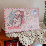 Enveloppe Père Noël dressée sur un napperon en crochet blanc, tampon Santa Claus Post Office visible