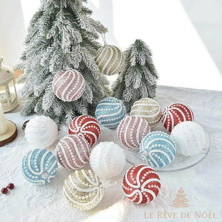 Boules de Noël perlées multicolores suspendues et posées devant deux petits sapins enneigés