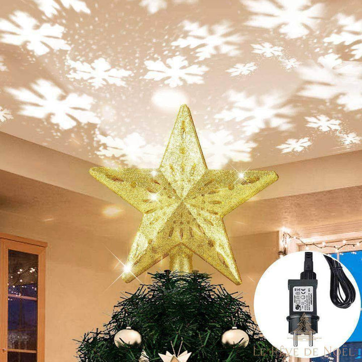 Cimier étoile dorée pailletée sur un sapin, projetant des flocons blancs au plafond d'une pièce claire en journée