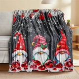 Plaid de Noël gris posé sur un canapé, motif de trois lutins à bonnets rouge et rose