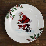 Assiette bordée de houx, Père Noël assis sur une cheminée en briques, chaton blotti en dessous