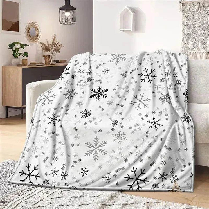 Plaid de Noël blanc à motif de flocons noirs et gris, sans personnage, posé sur un fauteuil