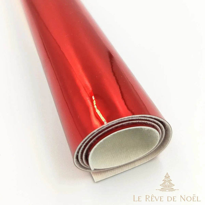 Papier cadeau métallisé rouge brillant, enroulé en rouleau avec un fil doré visible à la jonction