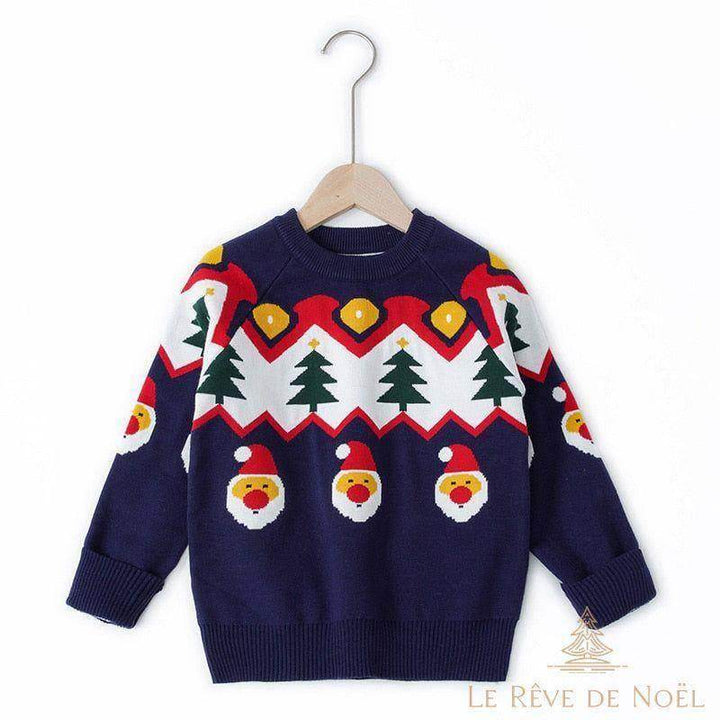 Pull enfant bleu marine à motif sapins et visages du Père Noël, sur cintre en bois