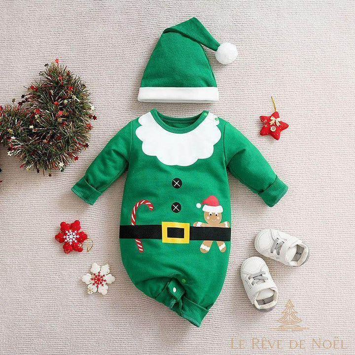 Barboteuse verte imitant un costume de Père Noël, bonnet à pompon blanc, posée avec des baskets