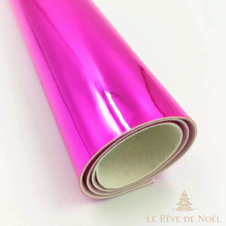 Papier cadeau métallisé rose fuchsia brillant, enroulé en rouleau montrant l'envers blanc du papier