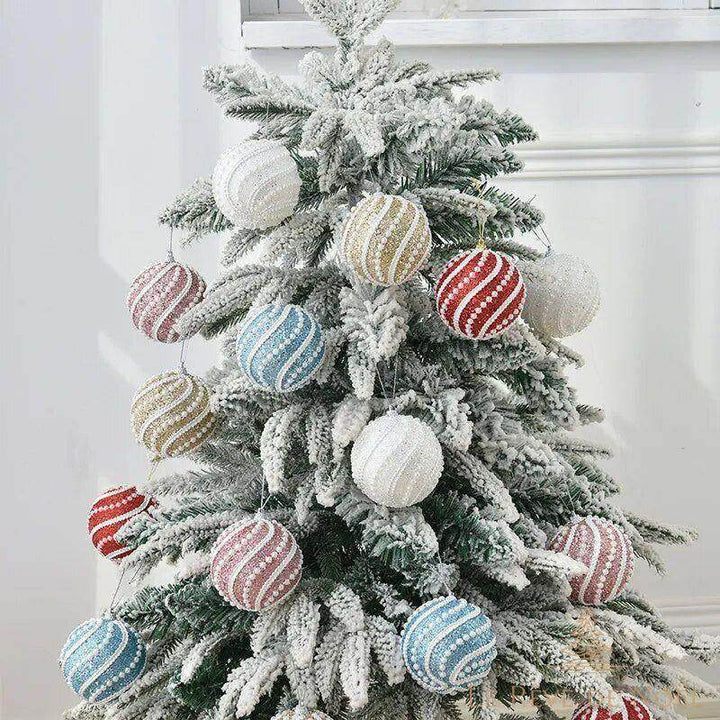 Boules de Noël perlées multicolores accrochées sur un grand sapin de Noël enneigé, vue d'ensemble