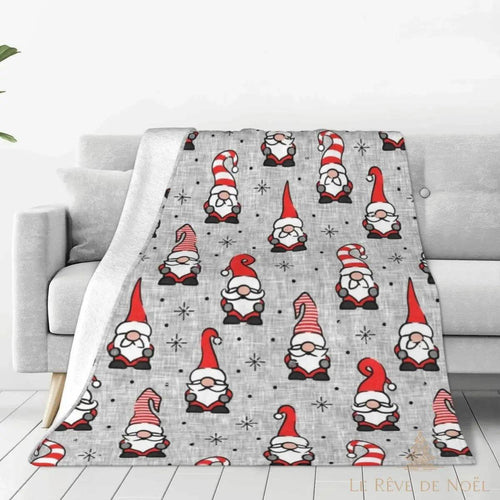 Plaid gris à motifs de lutins de Noël rouge et blanc, drapé sur un canapé gris clair
