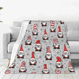 Plaid gris à motifs de lutins de Noël rouge et blanc, drapé sur un canapé gris clair