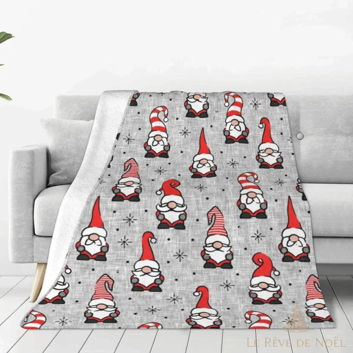 Plaid gris à motifs de lutins de Noël rouge et blanc, drapé sur un canapé gris clair