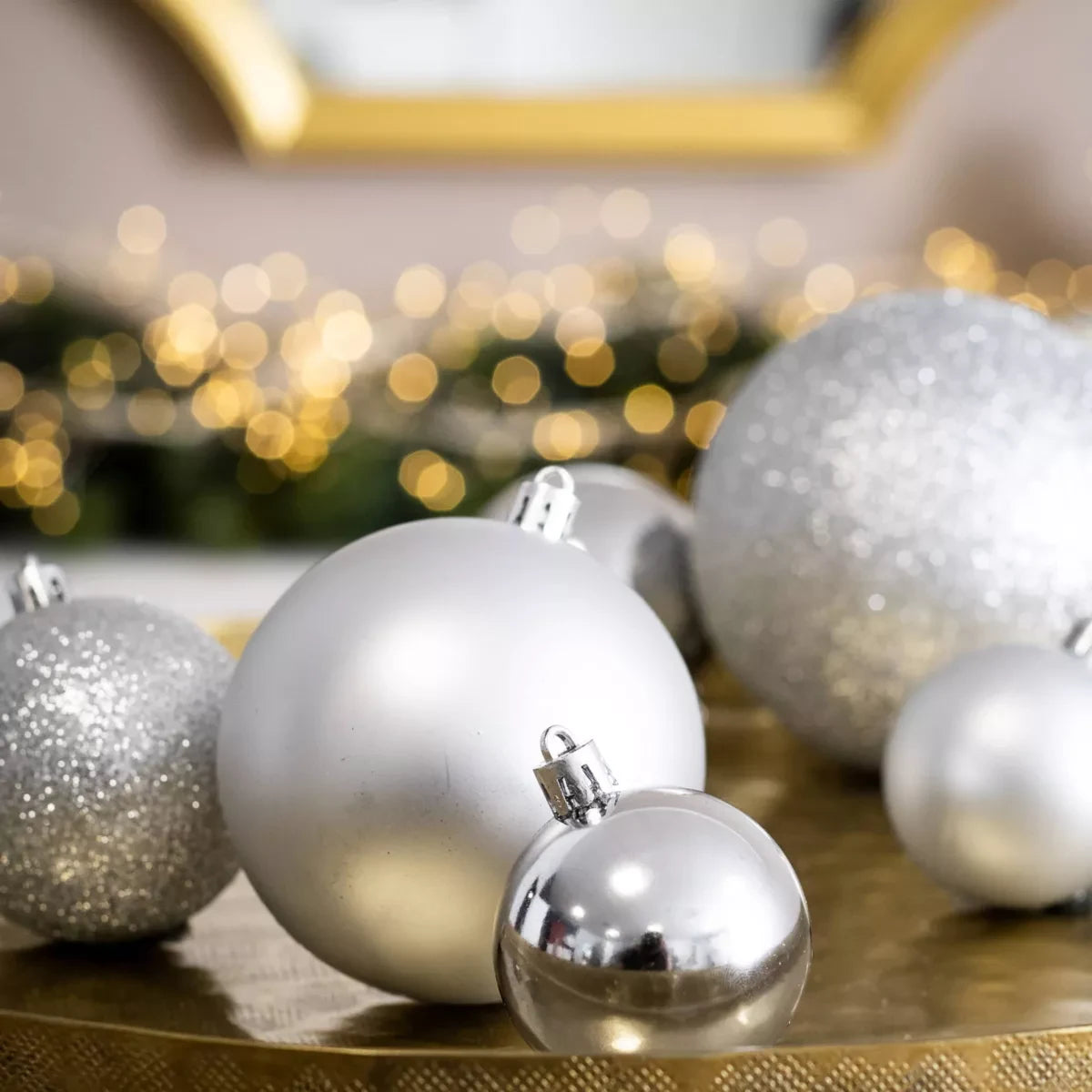 Boules de Noël argentées de trois tailles posées sur un plateau doré