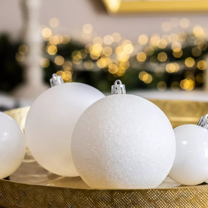 Boules de Noël blanches de trois tailles posées sur un plateau doré