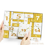 Mains tenant le calendrier beauté blanc et or aux tiroirs numérotés
