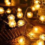 Guirlande lumineuse à épis blancs allumée, boules duveteuses dorées posées sur un panier en osier