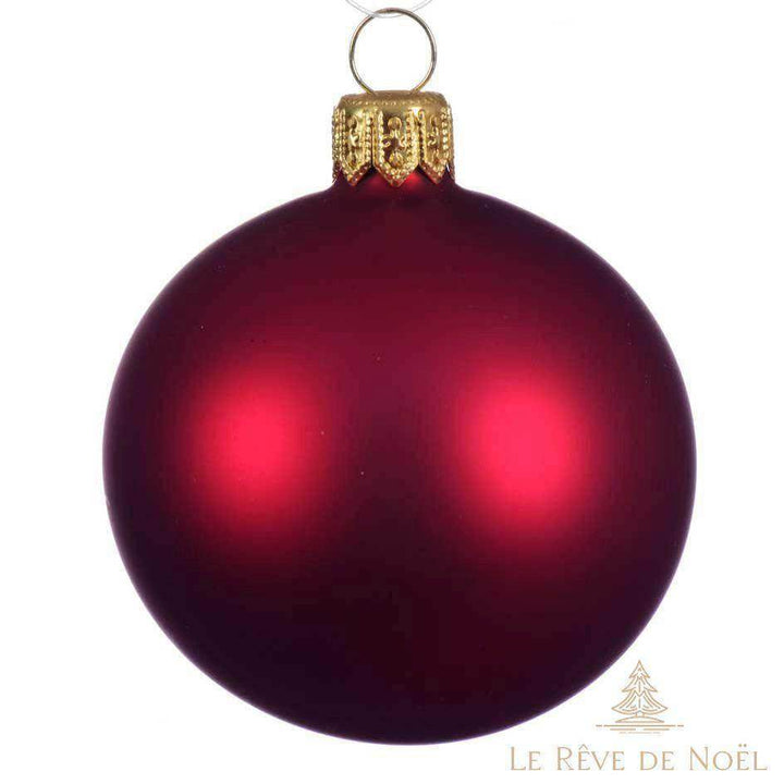Boule de Noël bordeaux mate en gros plan, capsule dorée, sur fond blanc