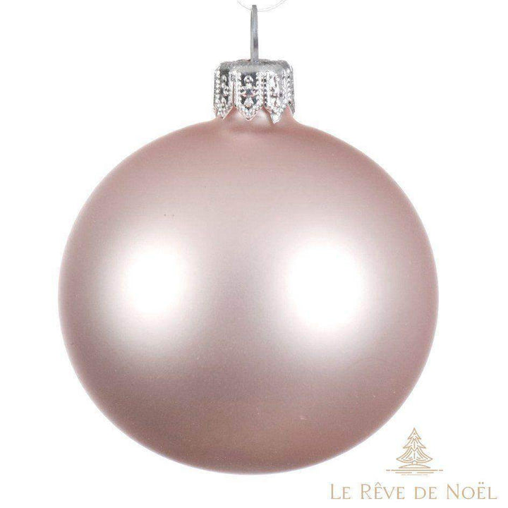 Boule de Noël rose poudré mate en gros plan, capsule argentée, sur fond blanc